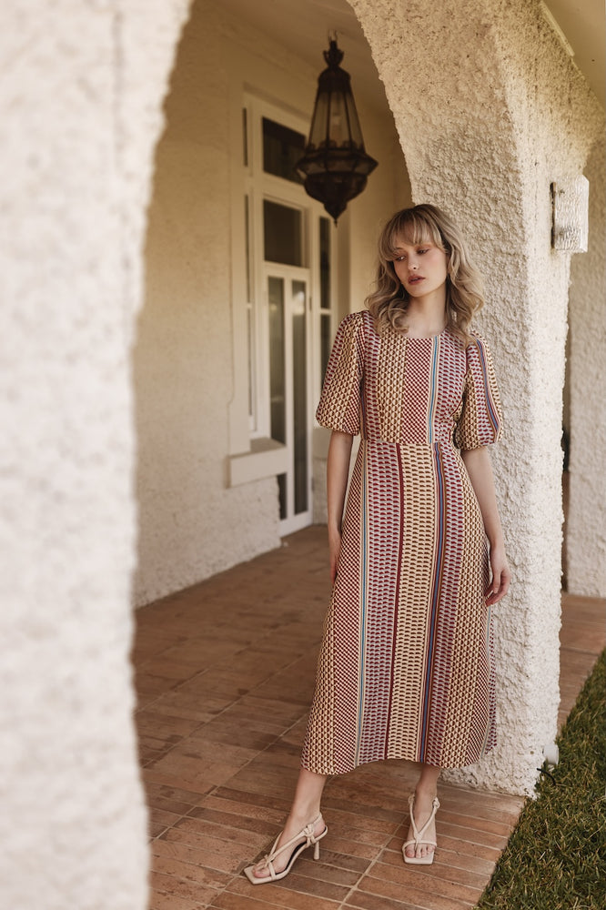 
                      
                        Woman in Mod Resort dress standing in front of a white building with an archway.
                      
                    