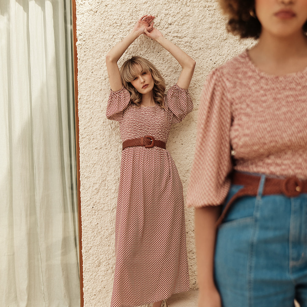 
                      
                        Woman in a Shirred dress and denim shorts standing in front of a textured wall.
                      
                    