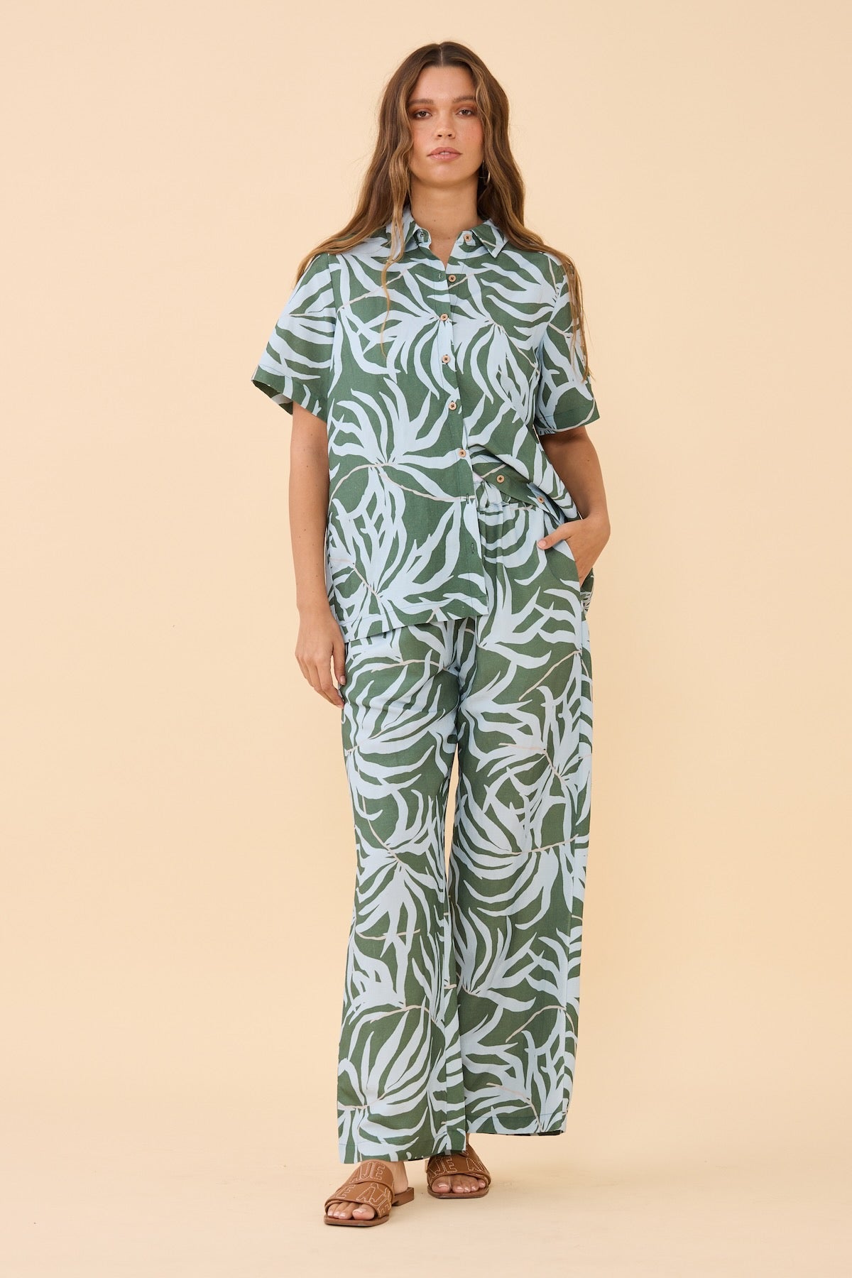 Woman standing wearing the matching Frock Me Out Lets Be Fronds Shirt and Pant set 