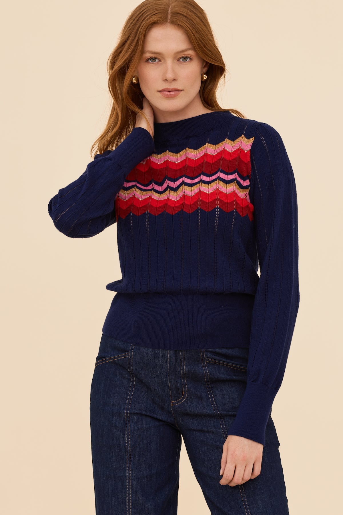 Woman wearing a navy sweater with a colorful pattern on a beige background