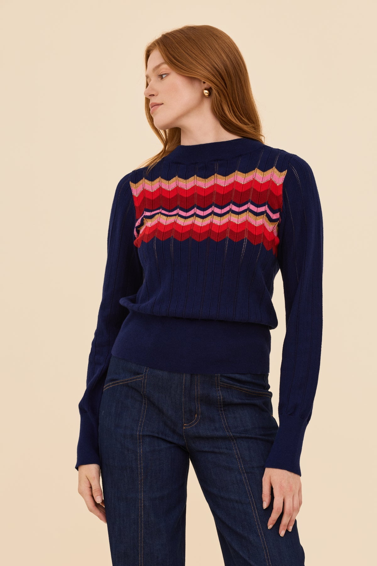 Woman wearing a navy sweater with a colorful pattern on a beige background